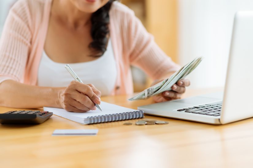 A budget planner is a powerful tool to stop financial insecurity and develop a better sense of money. A woman at the desk budgeting her money.