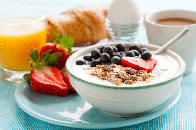 A healthy breakfast, a bowl of yogurt, muesli, fruit. Plus a boiled egg, orange juice and coffee.