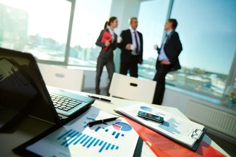 Medium-term financial goals are those you want to achieve within one to five years. A group discussing close to a desk with financial papers.