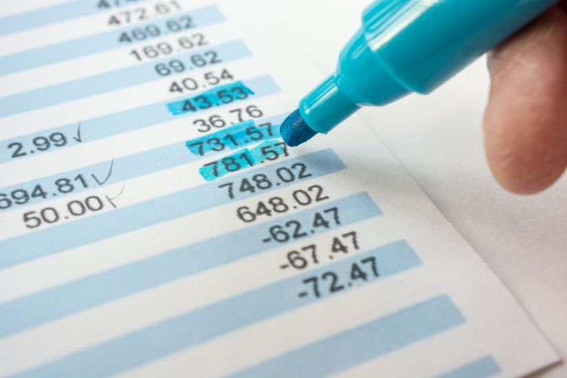 Review Bank Statements. Aclose-up of a blue marker and bank statements.