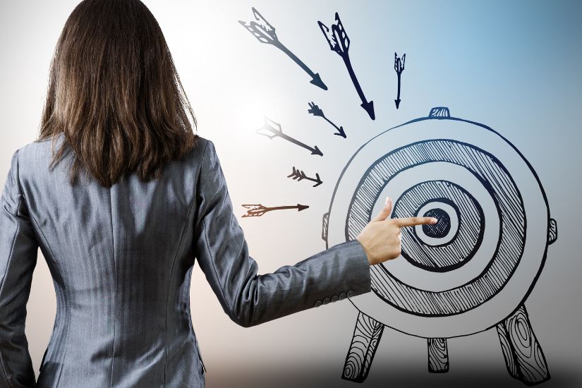 Achieving financial goals requires discipline, commitment, and smart strategies. A woman pointing in the centre of a dartboard.