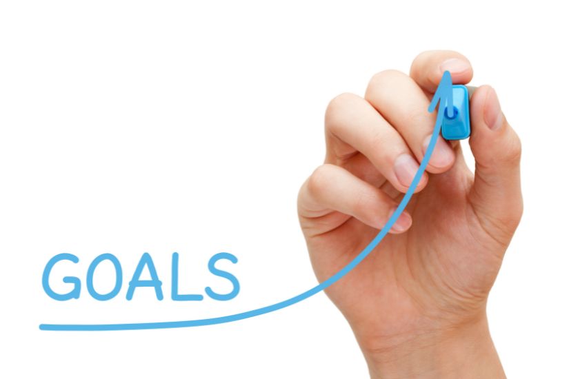 Your 1-year goal that brings you closer to your big life goal. To make it more realistic, especially regarding your finances, it's necessary to define at least one annual goal. A hand painting a goal.