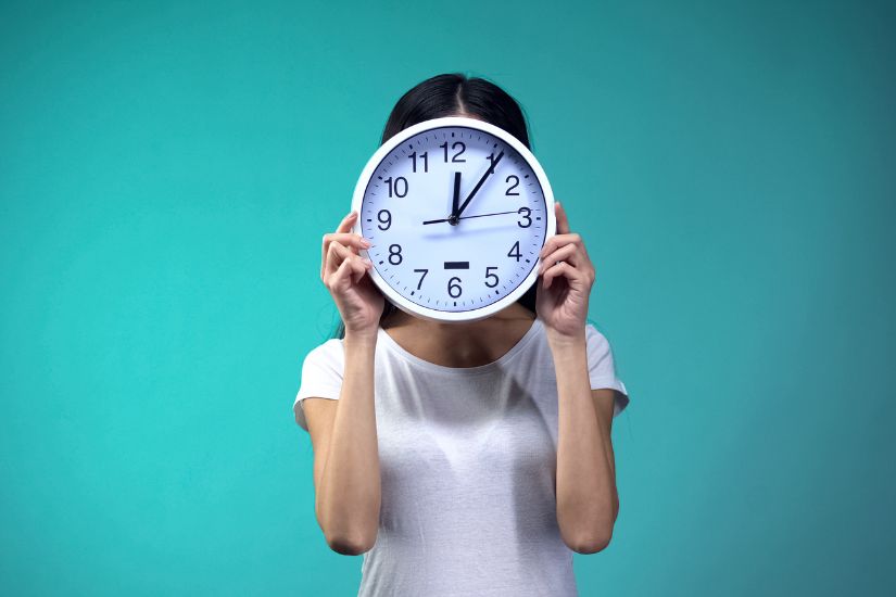 Creating a daily routine for entrepreneurs to be successful is a personal journey. A woman holding a clock in her hands.