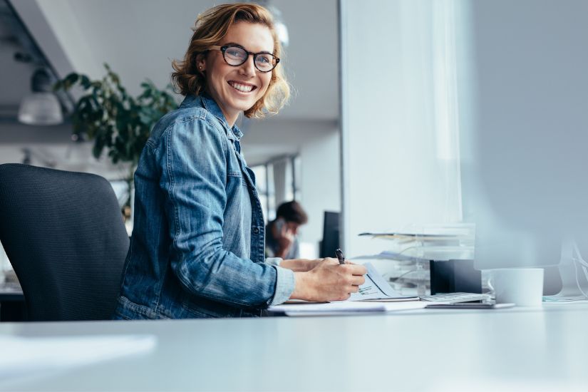 Imagine having complete control over your money—knowing where every dollar goes and seeing it work toward your goals. Engaging image of a woman confidently managing finances, possibly at a desk with a notebook, pen, and laptop.